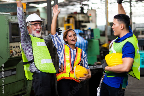 Man and Woman engineering wearing safety goggles and hard hats giving high five and celebrating success. Metal lathe industrial manufacturing factory © NVB Stocker