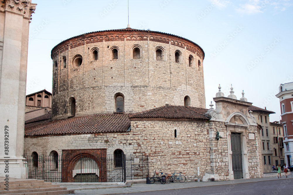 Panoramic view of Paolo VI square in Brescia, Lombardy Region - Italy. Sunset scene with clear sky, a stone church tower on the right and bricks houses around the square.
