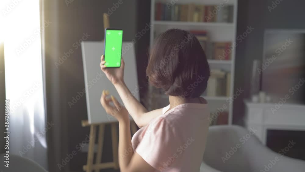 Middle aged woman talk on the phone by videochat. Videochating at home. Quarantine conception.Phone with green background. High quality 4k footage
