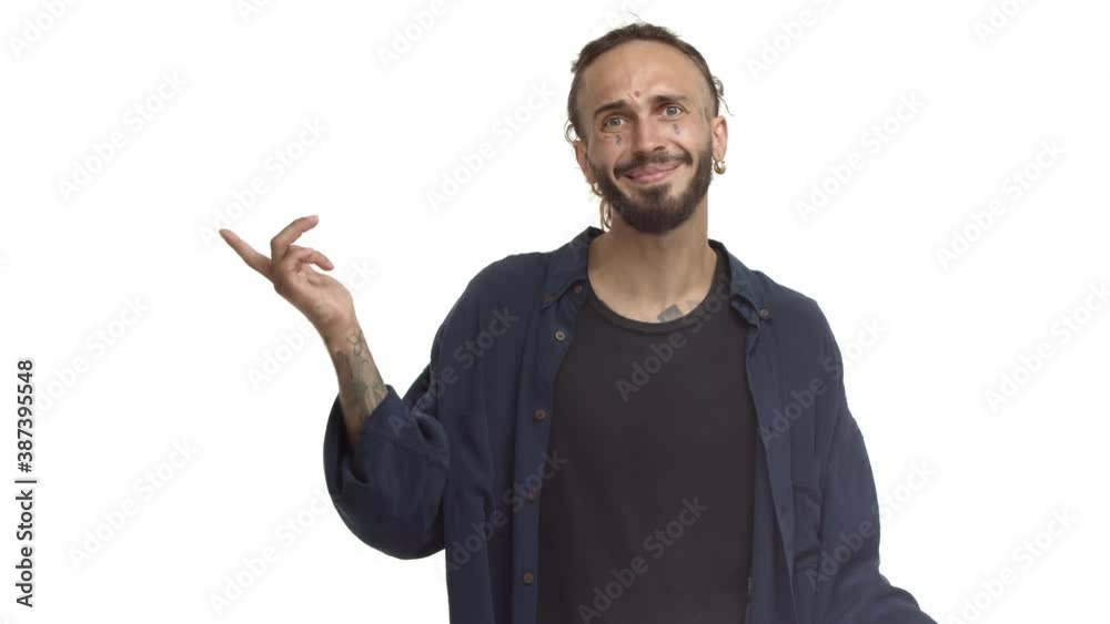 Attractive bearded male model with tattoos on face and body, cant hear you, pointing at ear and shaking head confused, standing against white background in casual shirt over t-shirt Attractive bearded male model with tattoos on face and body, cant hear you, pointing at ear and shaking head confused, standing against white background in casual shirt over t-shirt