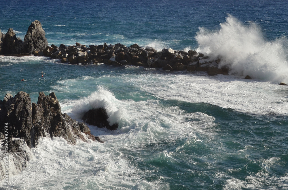Beautiful coast at Manarola, Cinque Terre, Italy with huge splash and happy swimmers.