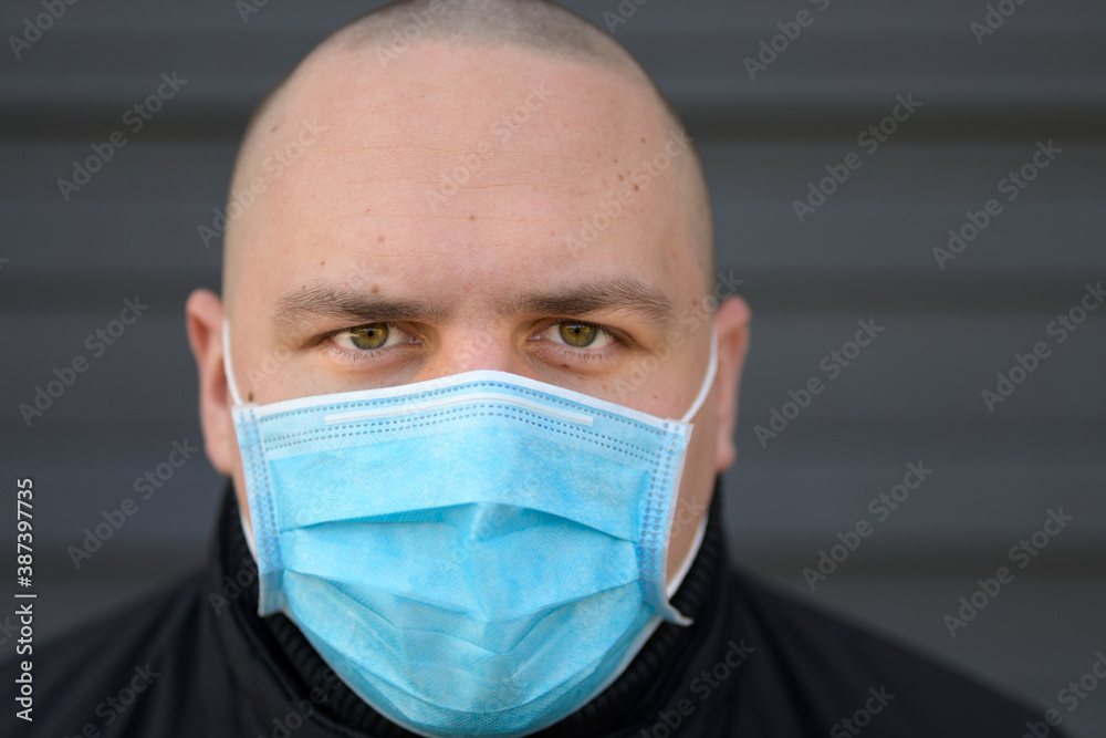 Headshot of a man wearing a surgical face mask Headshot of a man wearing a surgical face mask
