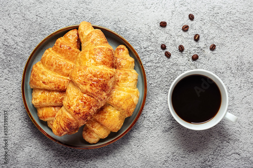 Fresh french croissants with chocolate on plate, coffee grains on gray granite background Continental morning breakfast Top view Flat lay