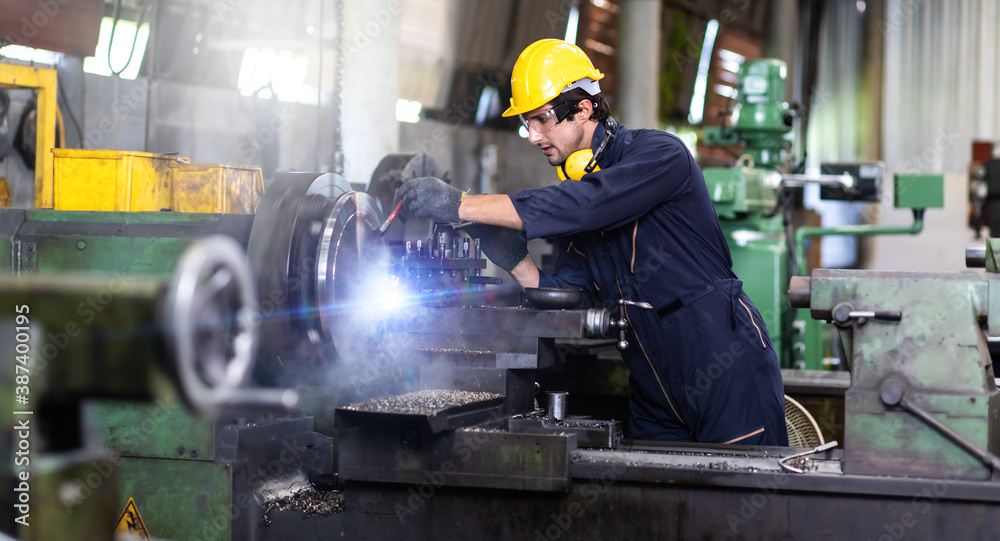 Man Worker at industrial factory wearing uniform and hardhats. Mechanical engineer working at lathe industry factory. Man Worker at industrial factory wearing uniform and hardhats. Mechanical engineer working at lathe industry factory.