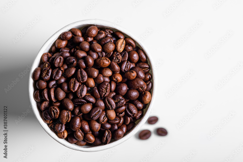 Fototapeta premium roasted coffee beans in white paper Cup on white background