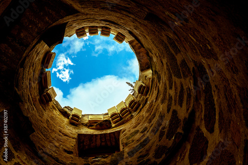 looking up to the sky or at the end of the tunnel there is a light  foreground tunnel and background the blue sky with clouds 