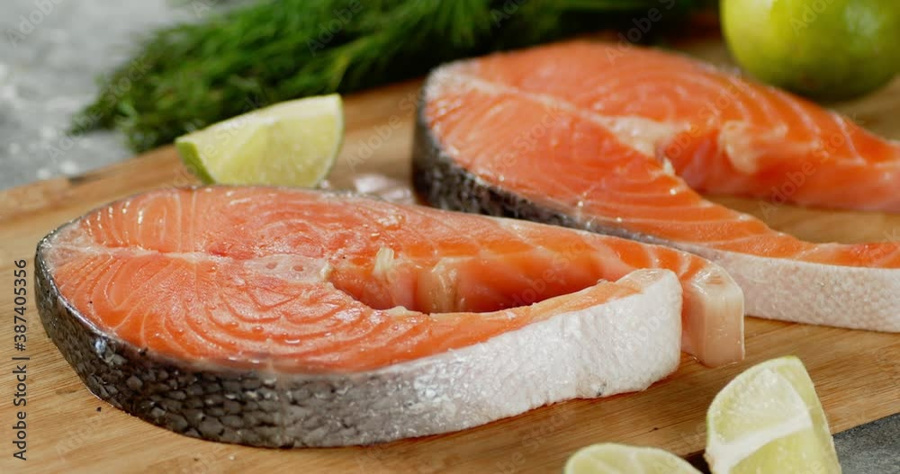 Fresh raw pieces of salmon rotate on wooden cutting board. Fresh raw pieces of salmon rotate on wooden cutting board.