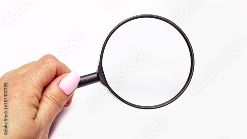Woman's hand holding a magnifying glass on a light background
