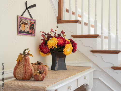 fall decor with flowers and pumpkin in entry next to staircase