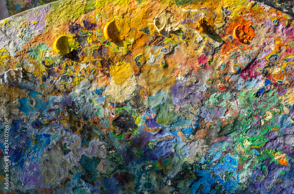 Stock Photo of a wooden painter palette with mixed and unmixed oil colours on sunlight. Concept art painter 