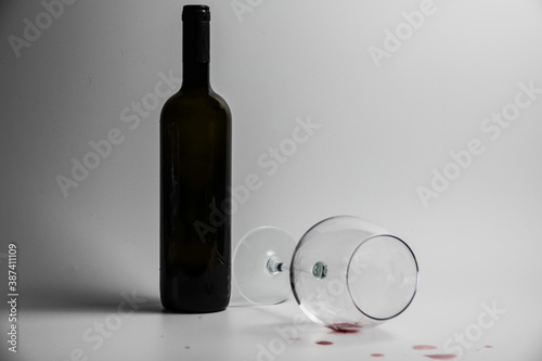 Wine bottle and overturned goblet                               