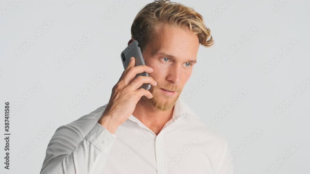 Handsome bearded man in shirt talking with business partner on smartphone over white background. Business talk. Modern technology Handsome bearded man in shirt talking with business partner on smartphone over white background. Business talk. Modern technology