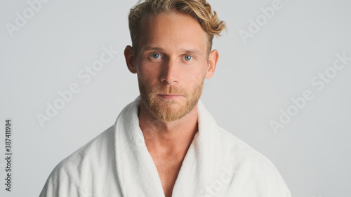 Handsome bearded man in bathrobe intently looking in camera isolated on white background