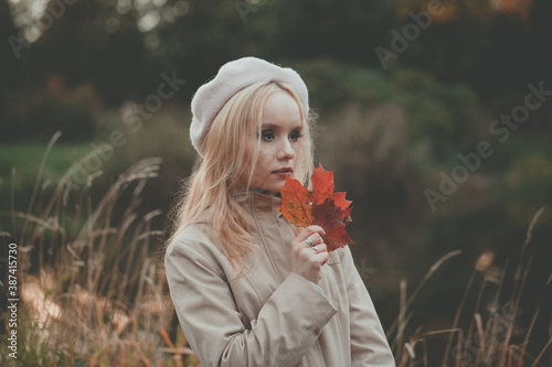 Pensive autumn woman with autumn leaves on fall nature background