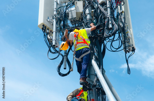 technician working on high telecommunication tower,worker wear Personal Protection Equipment for working high risk work,inspect and maintenance equipment on high tower. photo