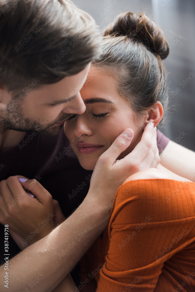 tender man hugging and touching face of depressed girlfriend at home