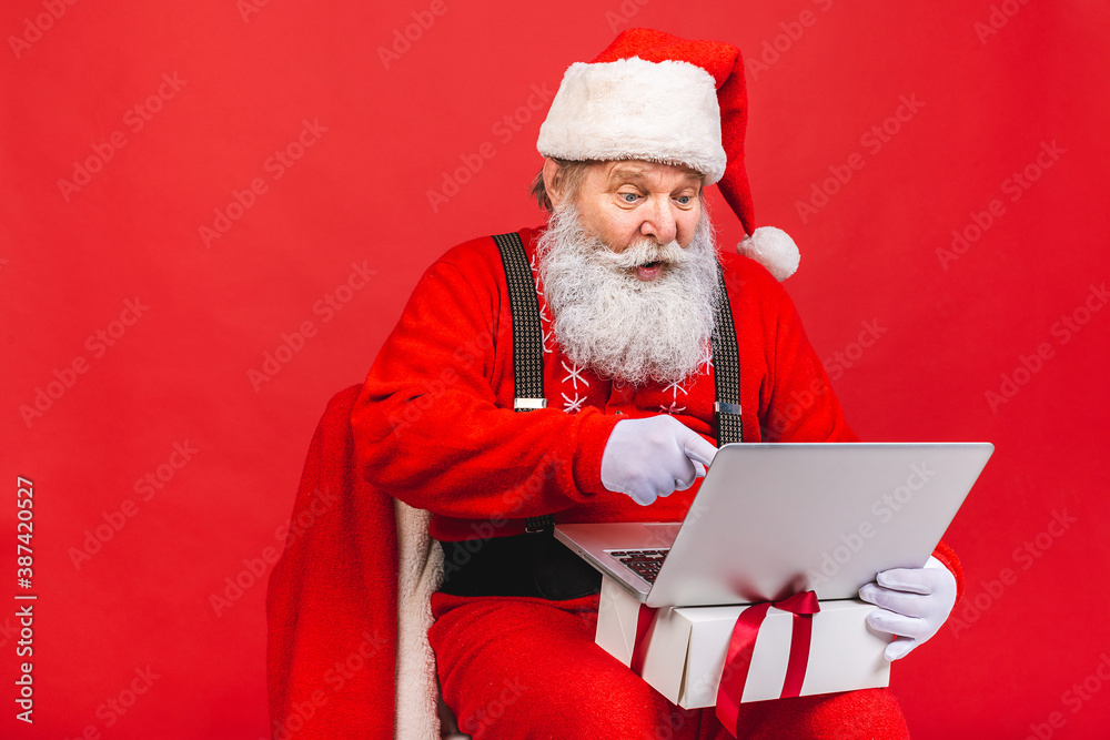 Naklejka premium Close up photo of funny funky overweight santa claus using laptop search christmas season discounts type congratulations isolated over red background.