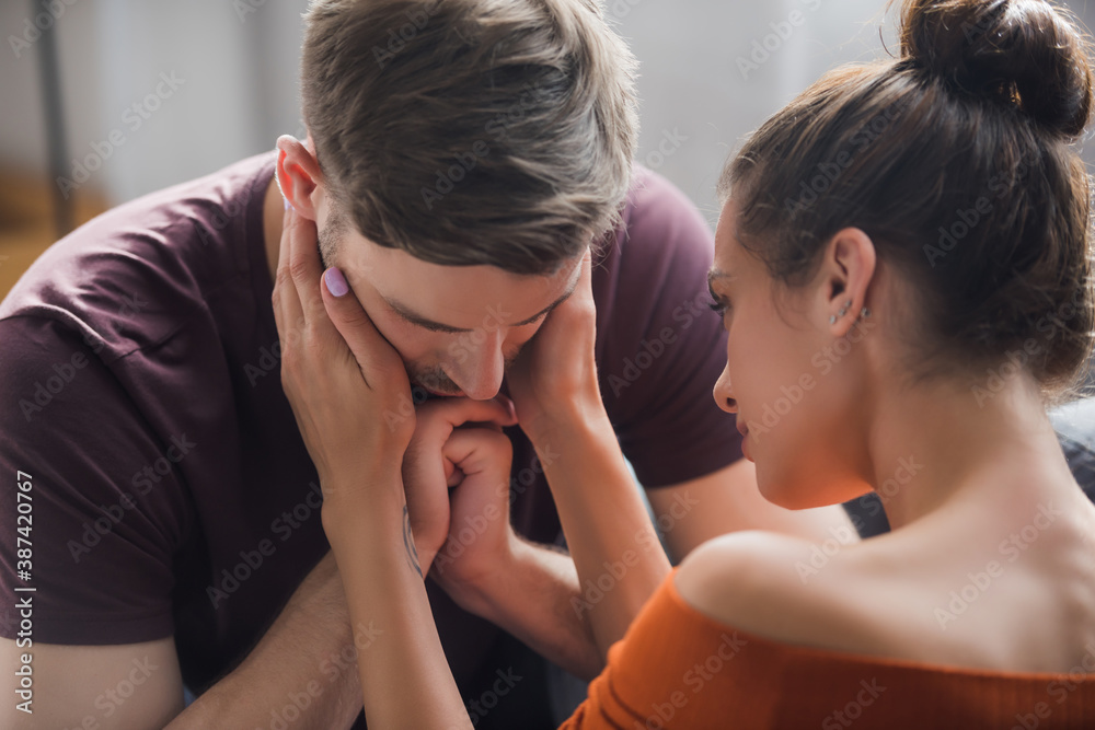 tender woman calming sad man by touching his face tender woman calming sad man by touching his face