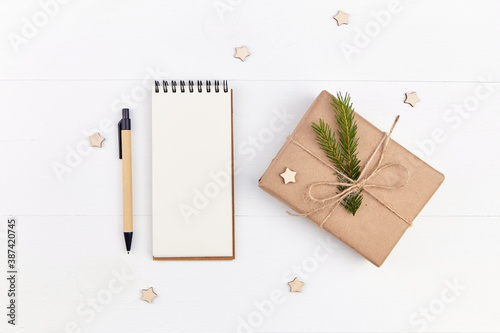Christmas creative layout with gift box and blank notepad on white background.
