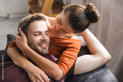 happy man with closed eyes embraced by tender, beloved woman