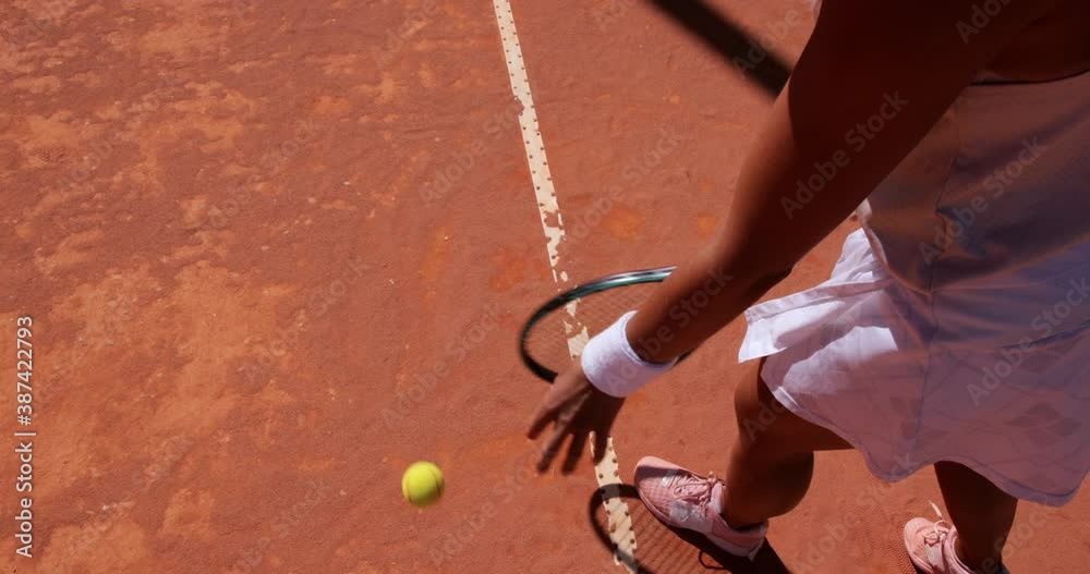 Woman bouncing ball before serving on tennis court