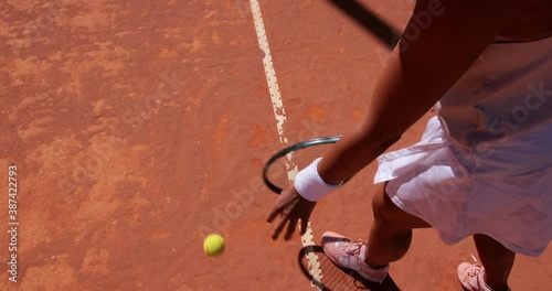 Woman bouncing ball before serving on tennis court