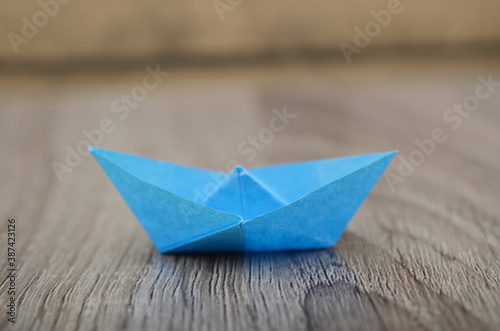 Origami blue paper boat isolated on woden background