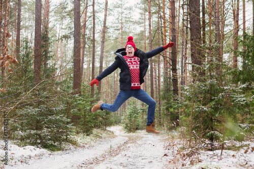 funny young man in red hat in winter forest