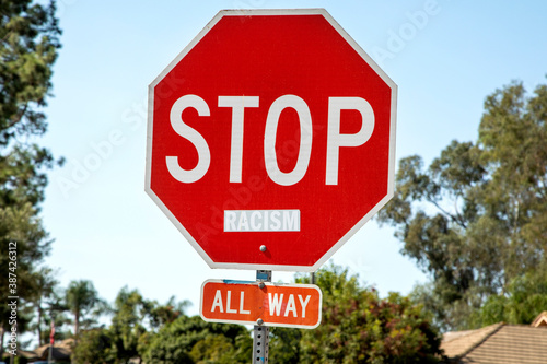 A stop sign with the word racism attached to the sign.