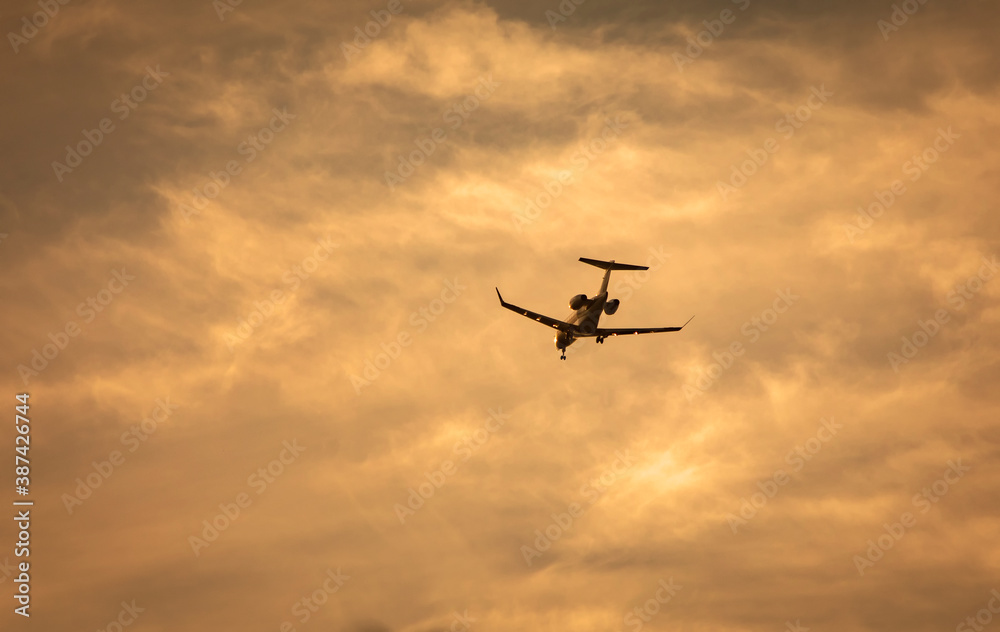 Private jet with landing gear down flying across blue sky with white cirrus clouds. Negative space is availalble.