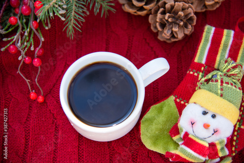 Coffee Cup on red knitted background with Christmas decorations