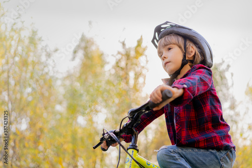 happy baby boy with a toothless smile on a Bicycle and wearing a protective helmet
