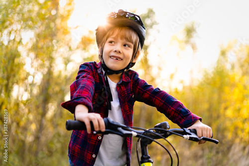 happy baby boy with a toothless smile on a Bicycle and wearing a protective helmet in the Park in autumn