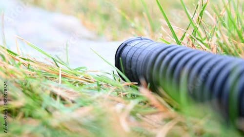 residential sump pump discharging water from the end of a flexible black hose shot with tripod