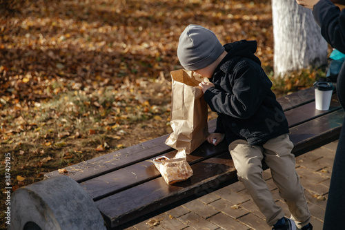 Kid is sitting in the autumn Park and eating with his mother. Lifestyle