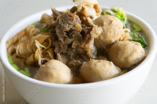 Thai Noodle (Tom Yum Noodles) has beef, meatballs, Ipomoea aquatica, Bean sprouts, in white bowl isolated on white background.