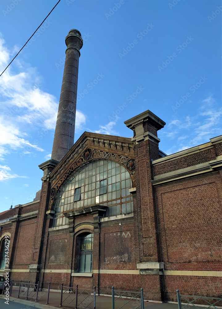 Patrimoine industriel - vieux bâtiment en briques rouges typique du Nord avec son entrée surmontée d'un fronton en verre et sa cheminée - Lille octobre 2020
