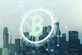 Double exposure of creative Bitcoin symbol hologram on Los Angeles city skyscrapers background. Cryptocurrency concept
