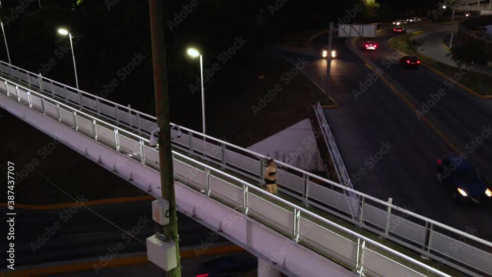 Toma aérea de joven atlética mexicana corriendo en puente sobre trafico de la ciudad de noche