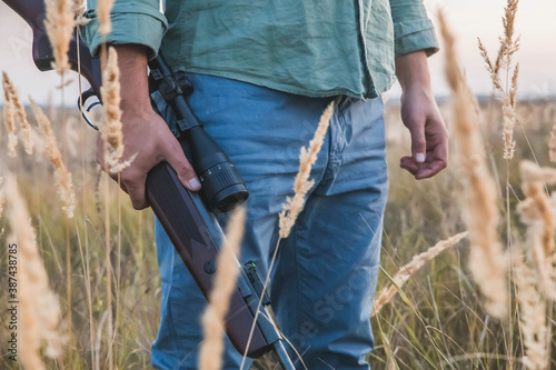 man with a rifle with a telescopic sight stands in a field