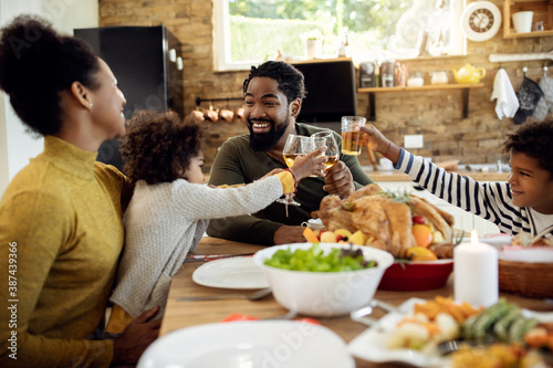 Happy black family toasting during Thanksgiving lunch at dining table.