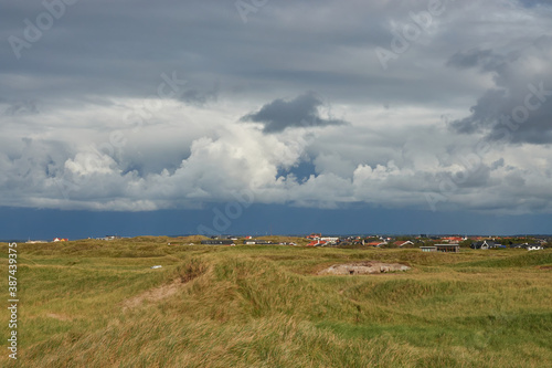 Landscape shot of green dunes and dramatic sky with hughes clouds. Denmark, Klitmoller (Cold Hawaii)