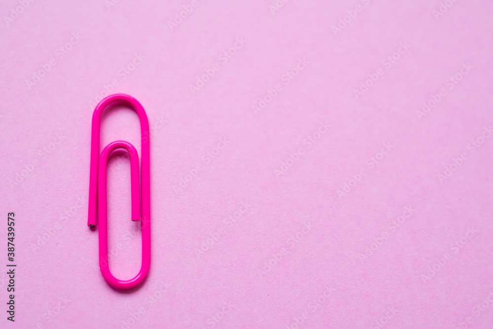 Pink paper clip over a smooth pink background, with copy space at the right side of the photo Pink paper clip over a smooth pink background, with copy space at the right side of the photo