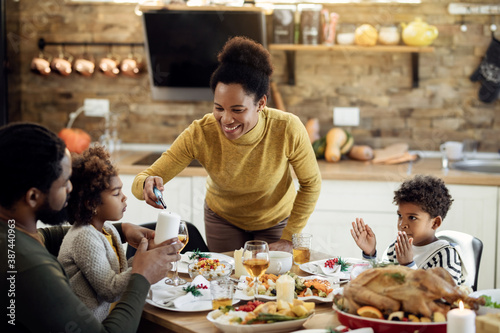 Happy African American family lightning candle during Christmas lunch at dining table.