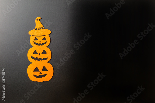 Three pumpkins with different facial expressions for halloween on black background.