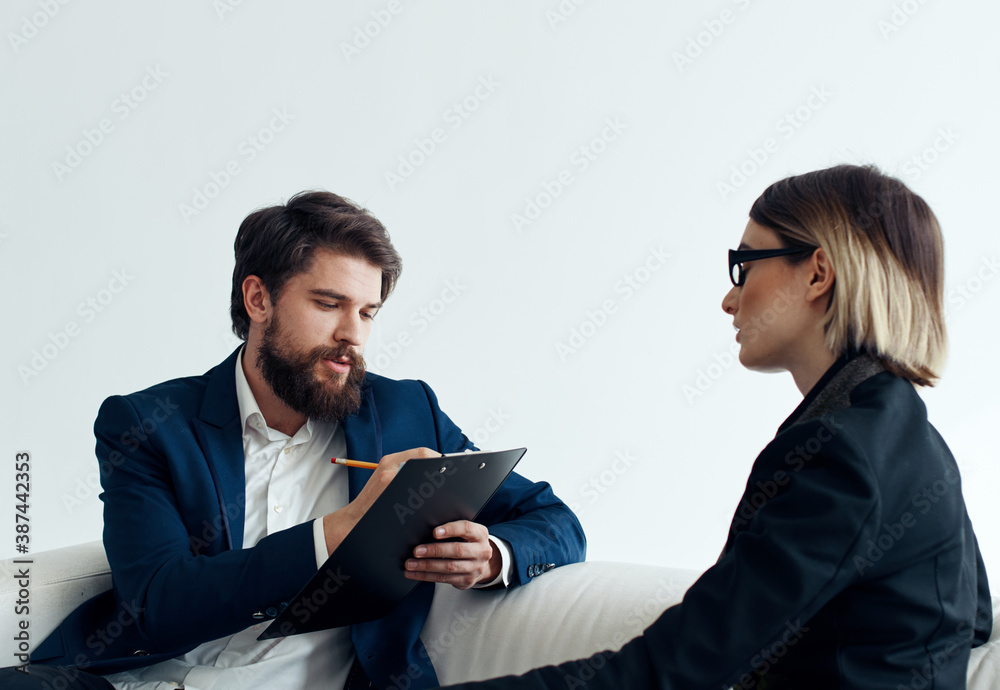 Business man with documents explains something to a young woman Sitting on a sofa indoors Business man with documents explains something to a young woman Sitting on a sofa indoors