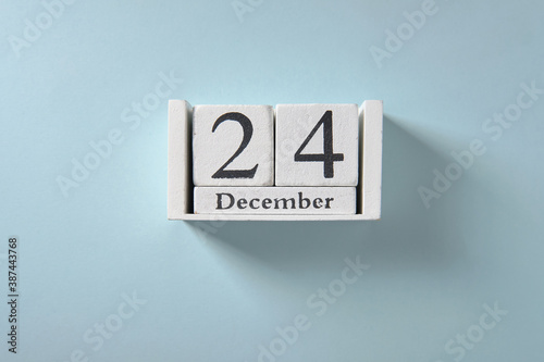 Wooden white calendar on blue background, date 24 December.