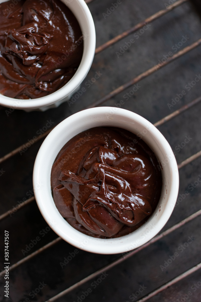 Chocolate dough for fondant in the white ramekin on dark background. Making french dessert. Lava cake. Chocolate dough for fondant in the white ramekin on dark background. Making french dessert. Lava cake.