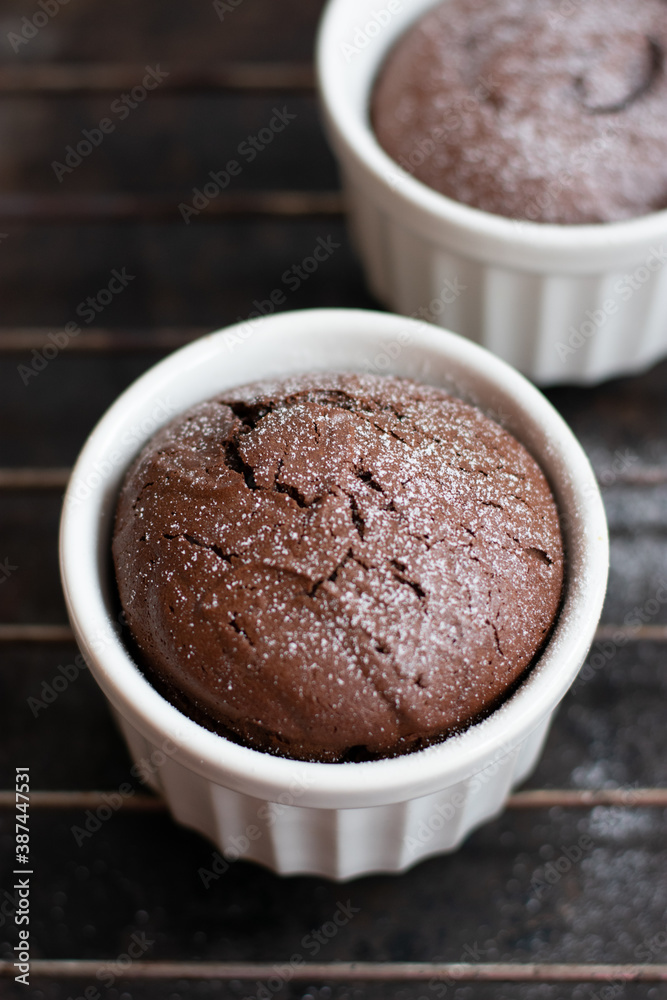Chocolate fondant in the white ramekin on the dark background. Lava cake. Chocolate fondant in the white ramekin on the dark background. Lava cake.