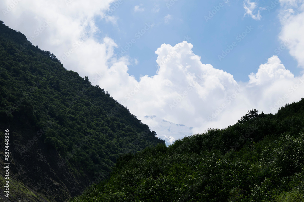 View of the mountains of the North Caucasus. Karmadon gorge. Mount Kazbek in the clouds. Mountains in the clouds in summer